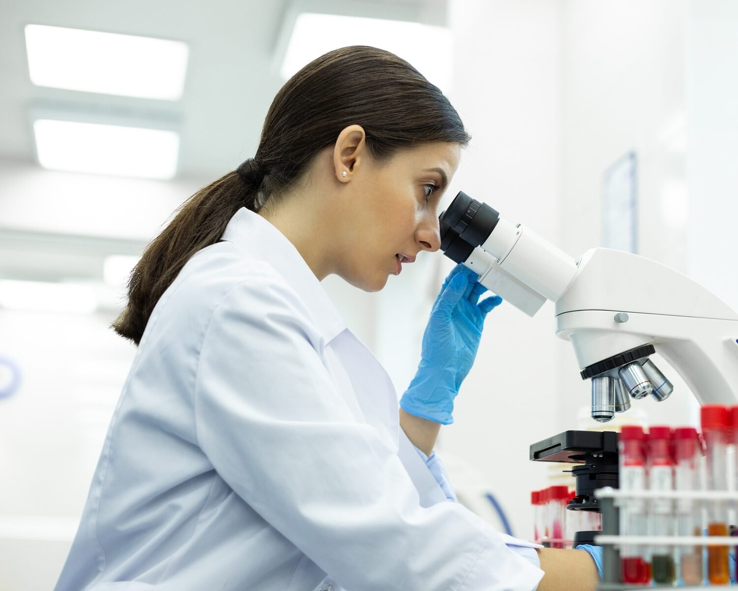 Concentrated brunette microbiologist working with lab equipment