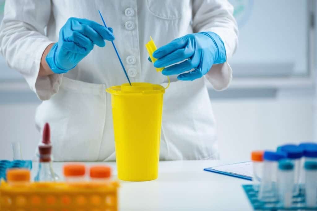 Disposing of laboratory consumables in hazardous waste container.