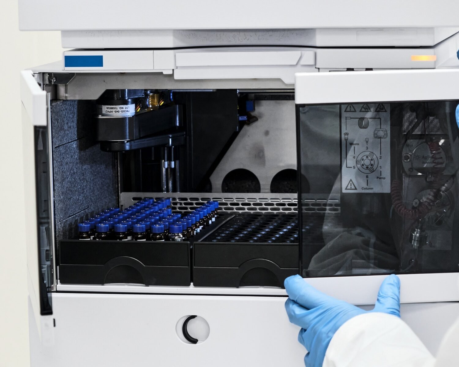 Close up scientist put sample in a glass vial with blue cap into the auto sampler rack in HPLC