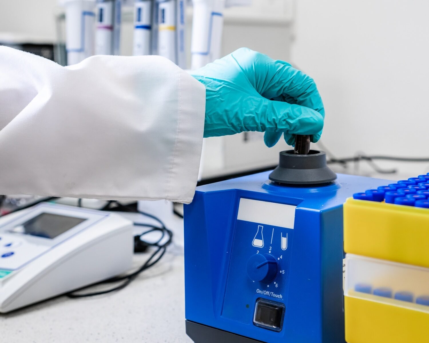 Laboratory worker mixes samples with a vortex mixer in preparation for HPLC analysis.